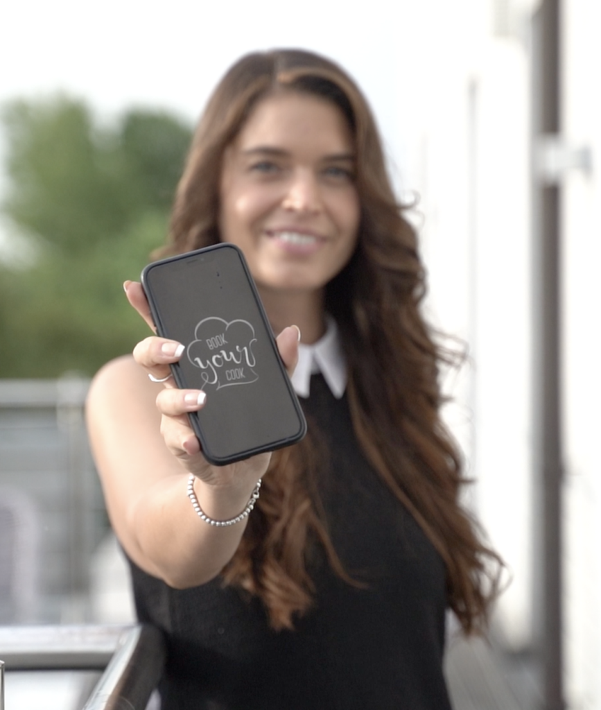Frau Tanja Knittel präsentiert BookYourCook auf dem Smartphone für exklusive Privatköche.